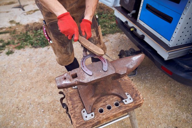 Blacksmith working on the anvil changing the horseshoe to a paw with tools