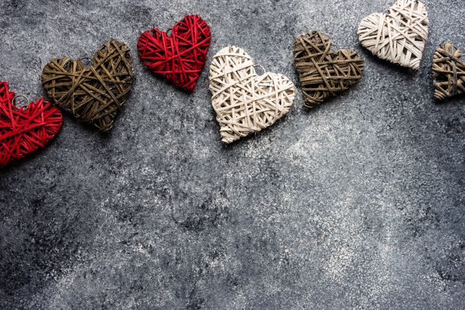 Thatched heart ornaments scattered on grey counter with copy space