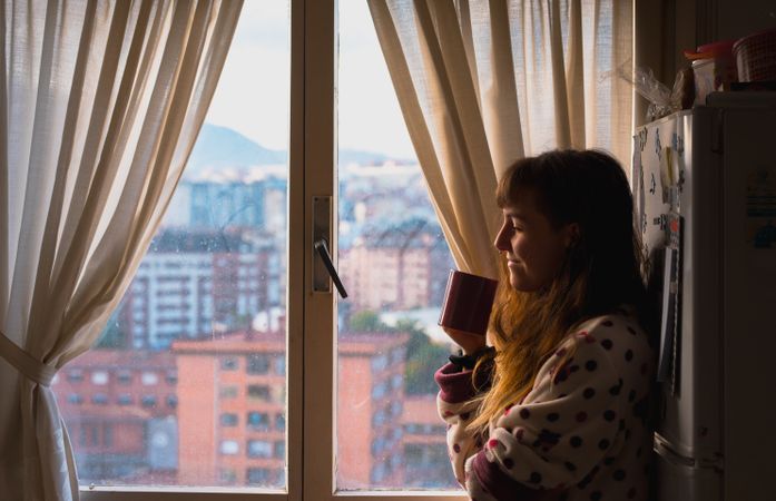 Woman enjoying hot beverage near fridge