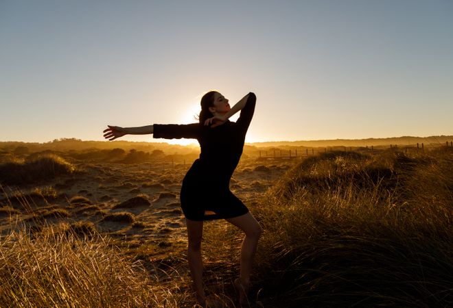 Woman posing between field at sunset