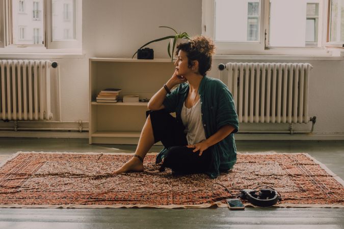 Peaceful woman meditating on floor at home