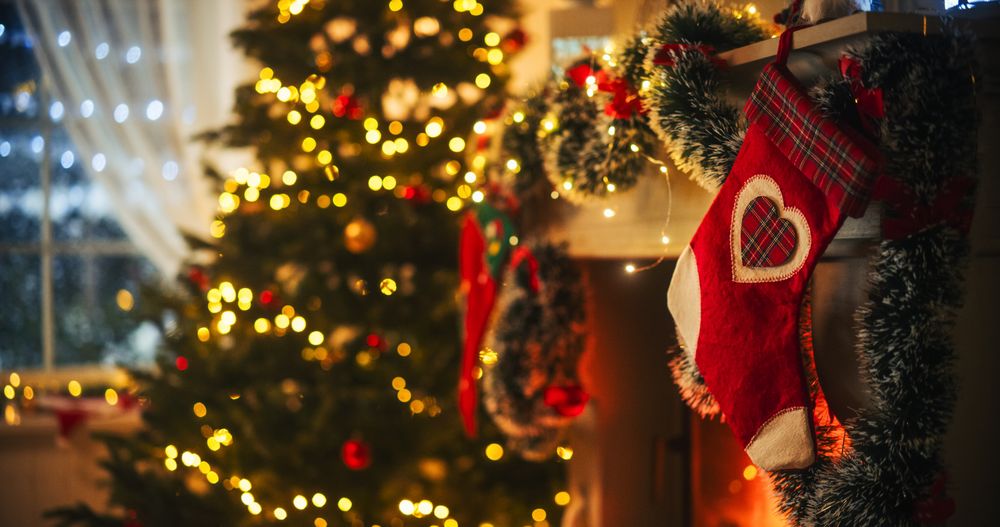 Empty Shot Depicting the Magic of Holidays on a Peaceful Snowy Christmas Eve: Close Up on Decorated Fireplace with Stockings Next to a Christmas Tree.