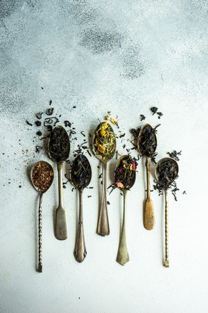 Delicate spoons with loose leaf tea on counter