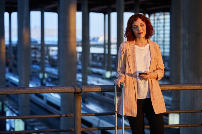 Smiling young woman holding phone at station