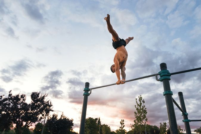 male athlete doing handstand on a bar in a calisthenic park