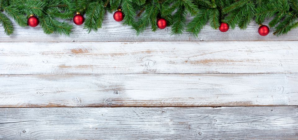 Christmas evergreen branches and red ornaments on vintage wooden planks
