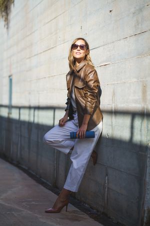 Chic female with thermos leaning on wall