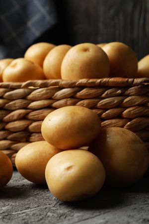 Vertical shot of wicker box of potatoes in dark room