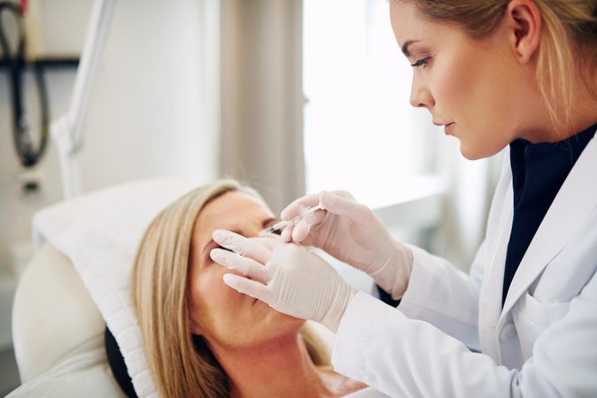 Female dermatologist injecting botox treatment into patient’s face
