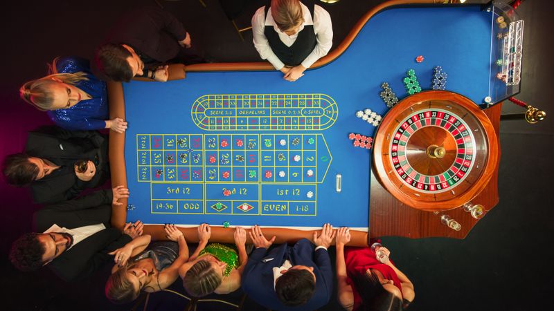 Top Down View: Luxurious Casino Male and Female Guests Putting Betting Chips on a Gambling Table, Trying to Predict the Outcome of a Roulette Game