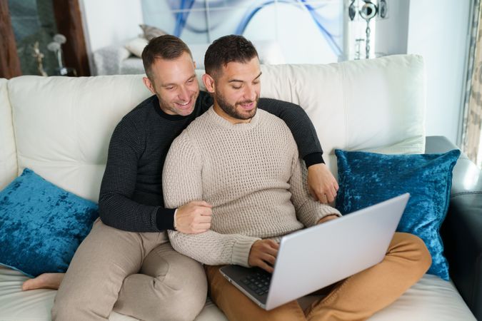 Two men on laptop together sitting at home