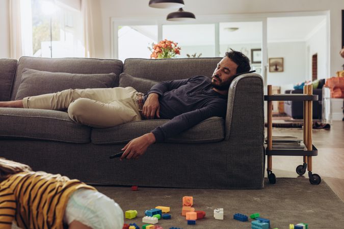 Man relaxing on couch with his kid playing on floor