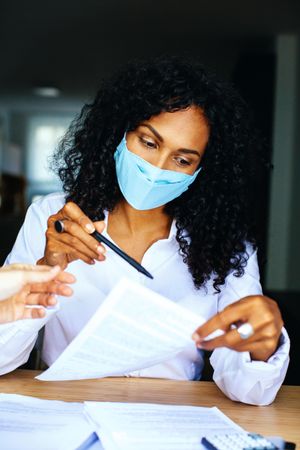 Woman going through documents at a work meeting while wearing a facemask