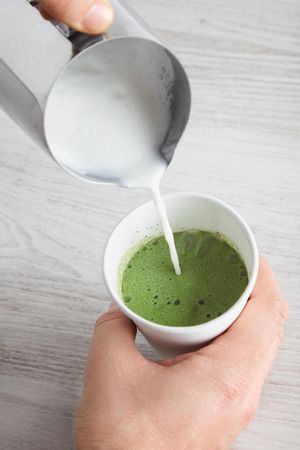 Milk froth being poured into matcha latte
