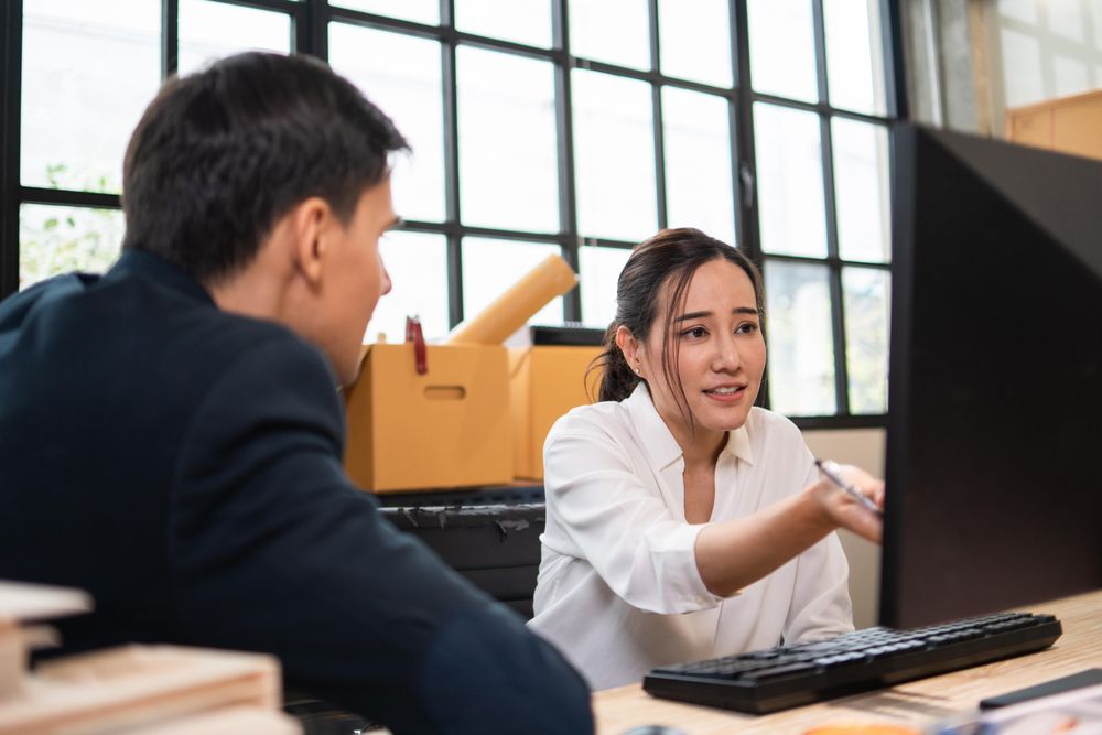 Female employing explaining her work to colleague and pointing to computer