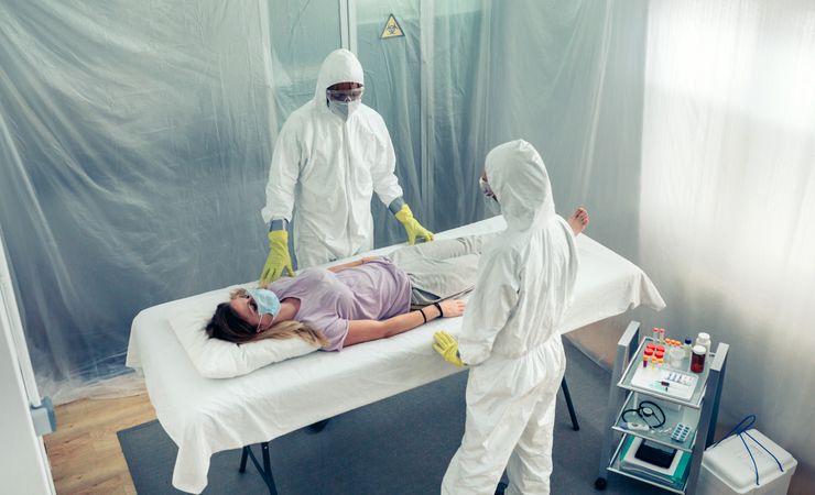 Doctors in bacteriological protection suit observing a patient lying on a gurney