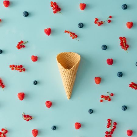 Waffle cone on blue background with berries