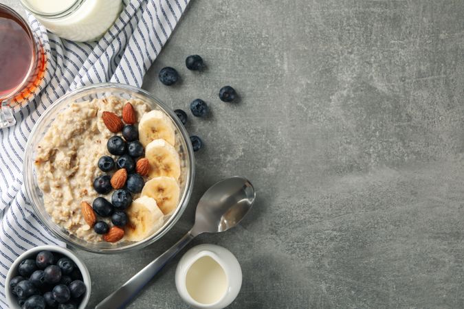 Composition with oatmeal porridge with fruits on gray background