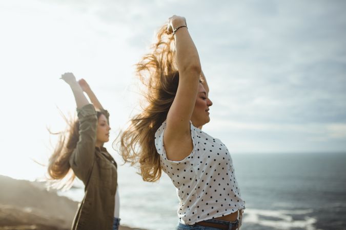 Happy female travelers enjoying freedom at seaside