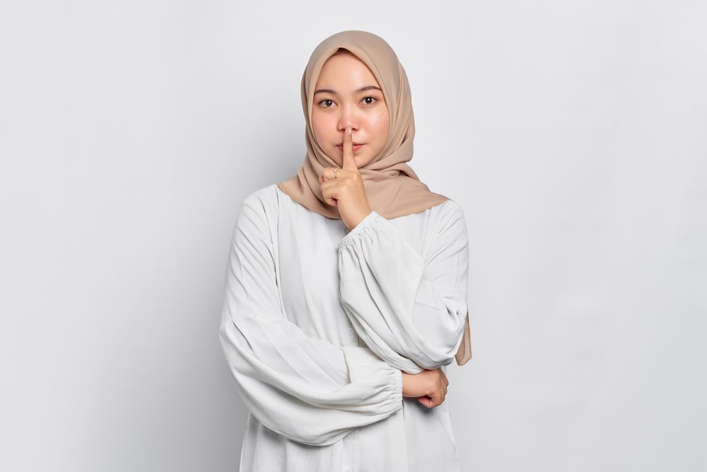 Asian female in headscarf with asking you to be quiet