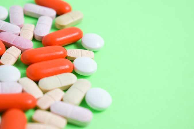 Pills and vitamins on green table with copy space