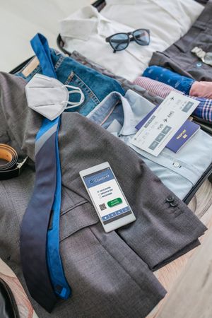 Businessman suitcase preparations for business trip with covid passport