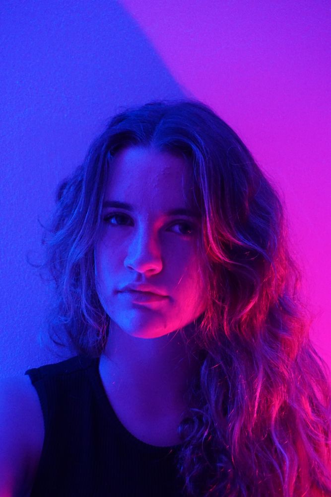 Portrait of teenage girl with long hair in purple lit studio