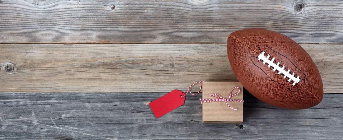 Father’s day gift box and football on rustic wooden planks