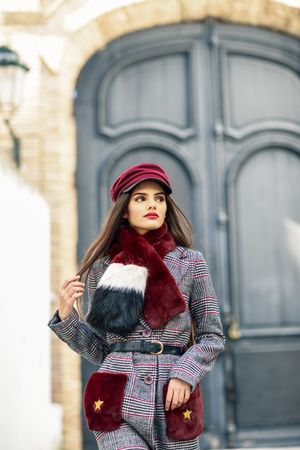 Woman standing in winter clothes in front of outside door looking in distance