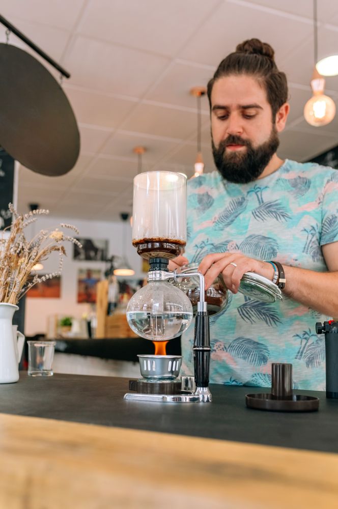 Barista skillfully preparing a specialty coffee in Japanese siphon coffee maker with precision