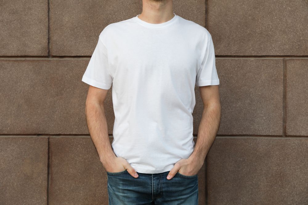 Men in blank t-shirt against building, space for text