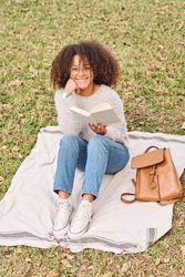 Cheerful Black woman with book in nature