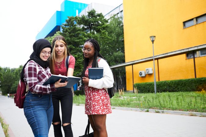 Multi-ethnic students checking a textbook on campus