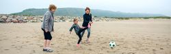 Three generations of females playing soccer on the beach
