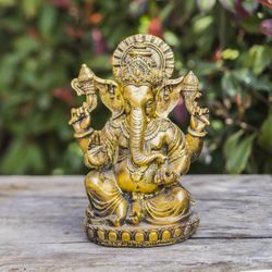 Ganesha statue sitting in meditating yoga pose on a trunk.