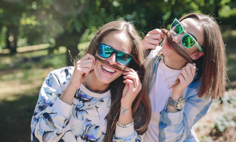 Women doing moustaches with hair and laughing