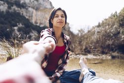 Couple holding hands on shore of lake
