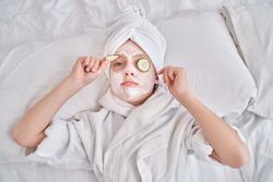 Boy with cucumber slices and facial mask at home