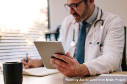Focus on digital tablet in hand of doctor sitting at his desk 5rO614
