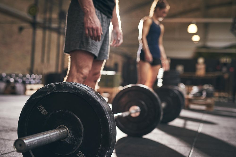 Close up of weight plate with athletes in the background