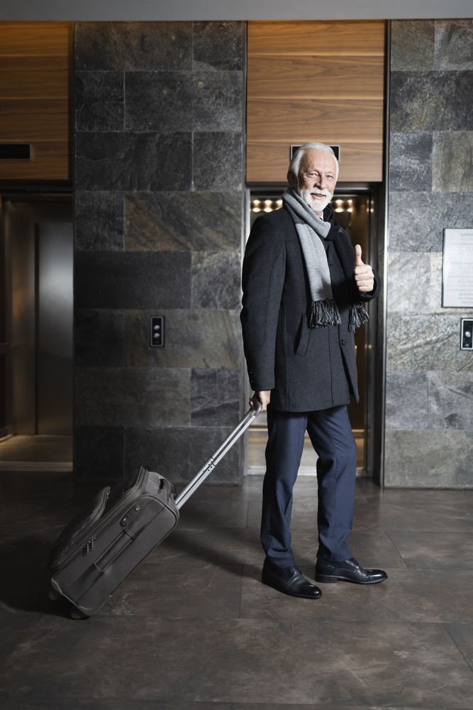 Man with rolling suitcase giving thumbs up