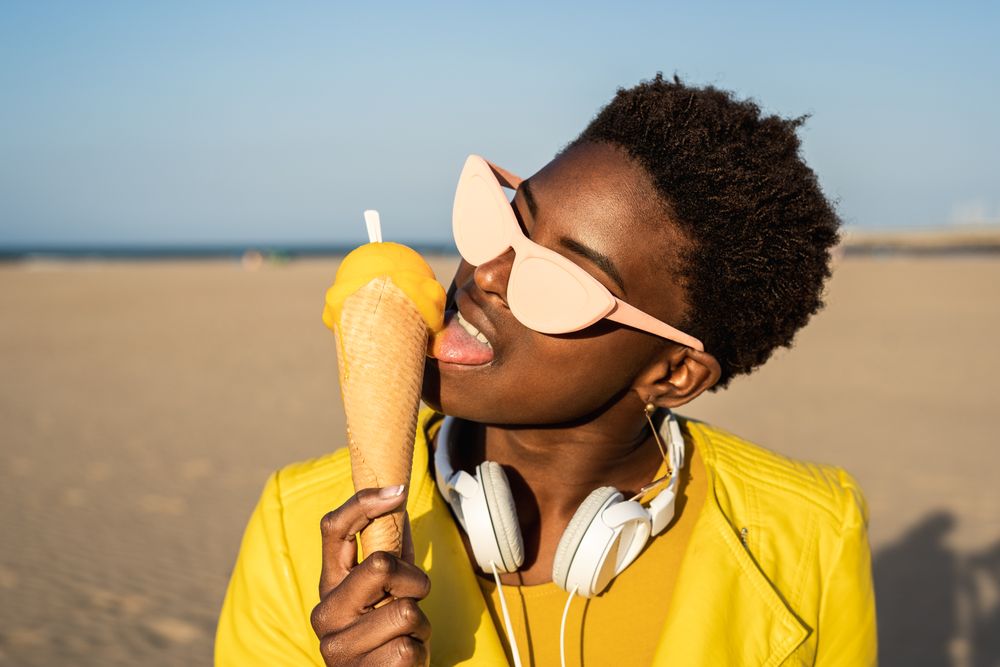 Cool female eating ice cream on beach