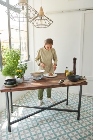Young female chef arranging steak tartare on plate before servin