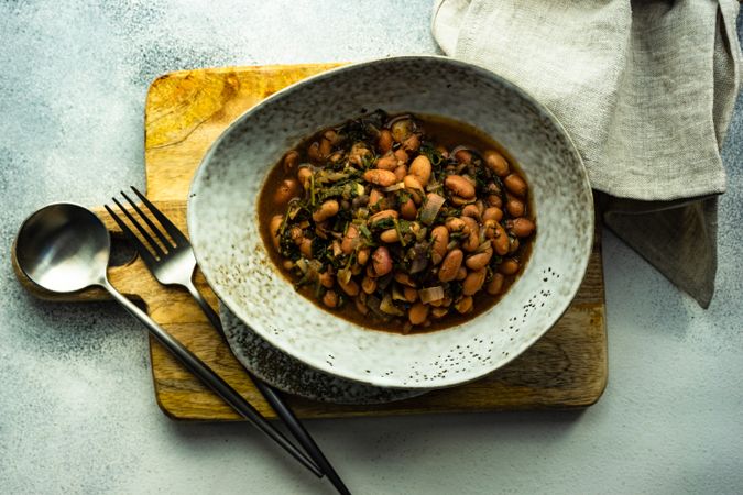 Top view of traditional Georgian bean dish - lobio, served in modern textured ceramic bowl on wooden cutting board
