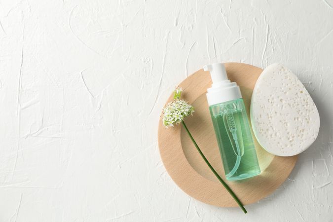 Lotion, allium flower and sponge on plain background, copy space