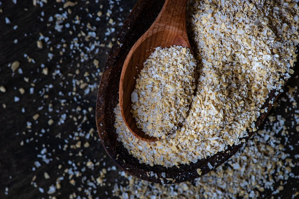 Top view with ground oats with wooden spoon