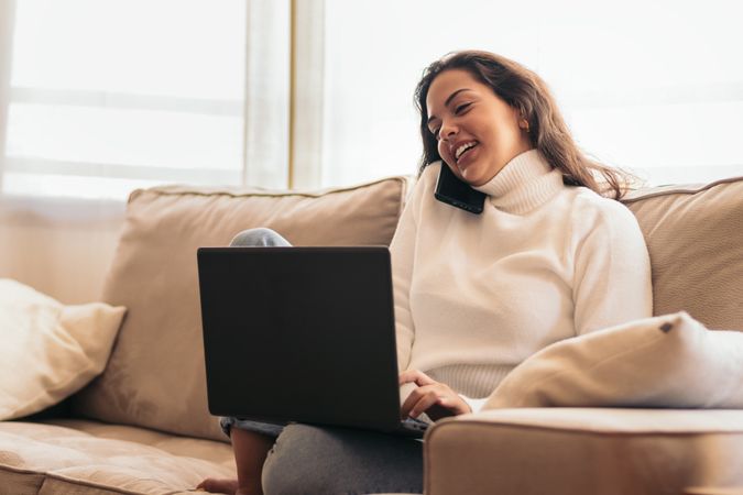 Remote Work and Communication: Young Woman Using Laptop and Smart Phone at home