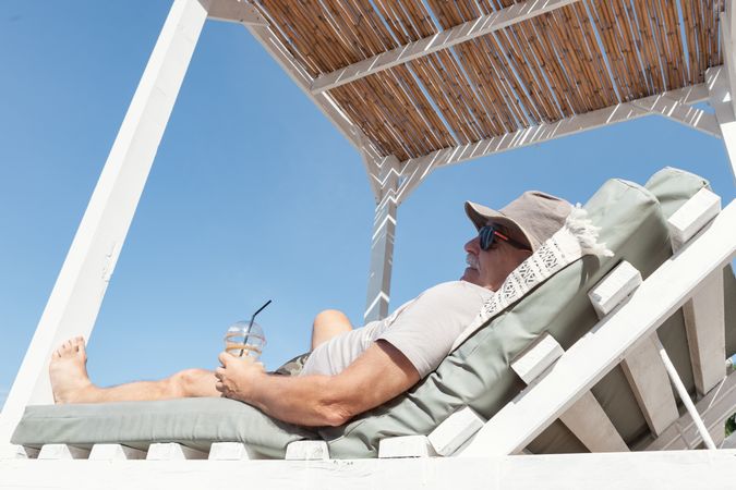 Man resting under umbrella and drinking fresh drink