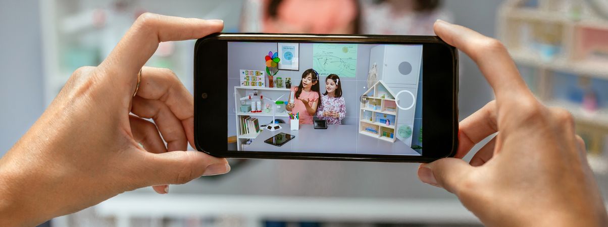 Teacher recording video in mobile of students showing led lamp in ecology classroom