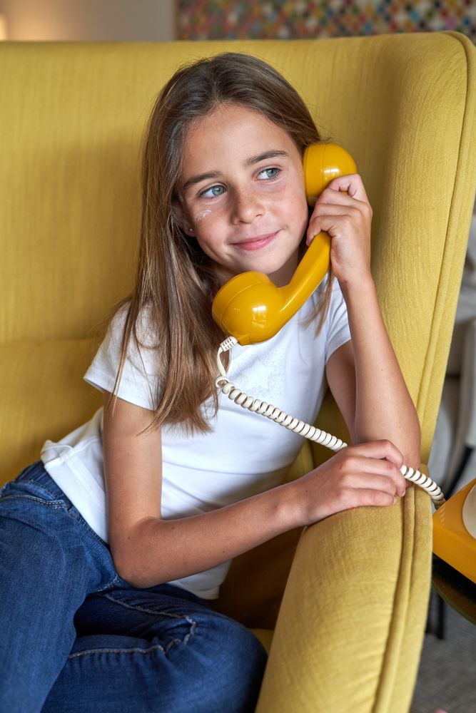 Positive girl speaking on vintage landline phone